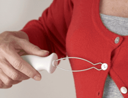Picture of a woman using a device to button her cardigan